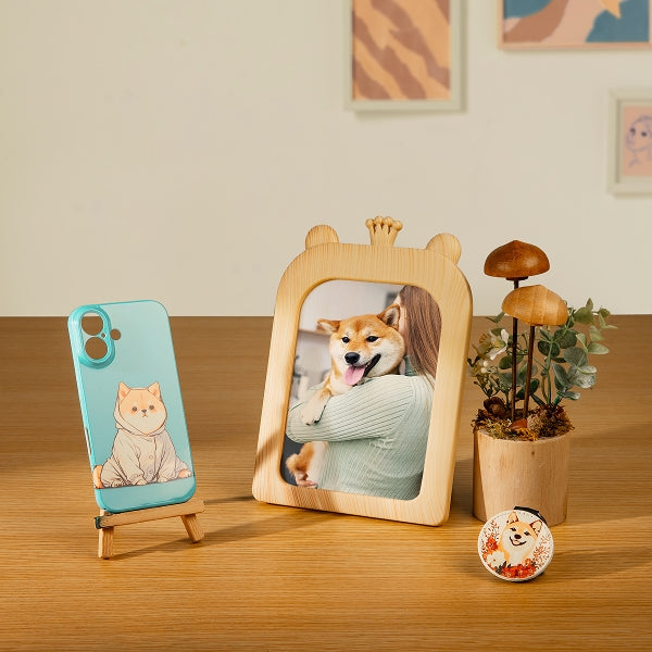 Wooden photo frame with a picture of a woman and a dog, next to a phone case and a small plant on a wooden surface.