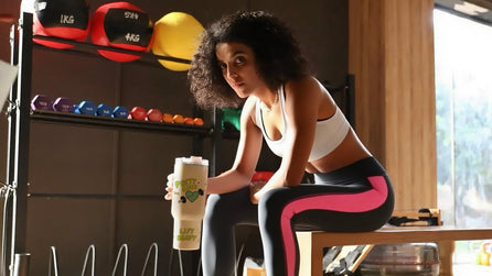Woman in workout attire holding a protein shake in a gym setting