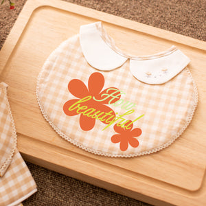 Baby bib with floral design and 'You are beautiful' text on a wooden surface