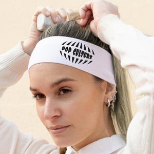 Woman wearing a white headband with 'Pop Culture' text, adjusting it on her head.