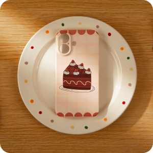 Phone case with cake design on a white plate with polka dots on a wooden surface