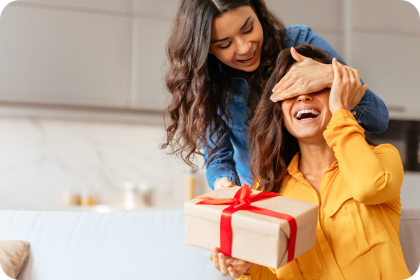 Two women with a gift box in a kitchen setting