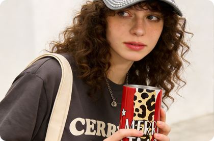Person holding a red can with leopard print design and 'Merry' text, wearing a dark sweatshirt with 'CEREBR' text.